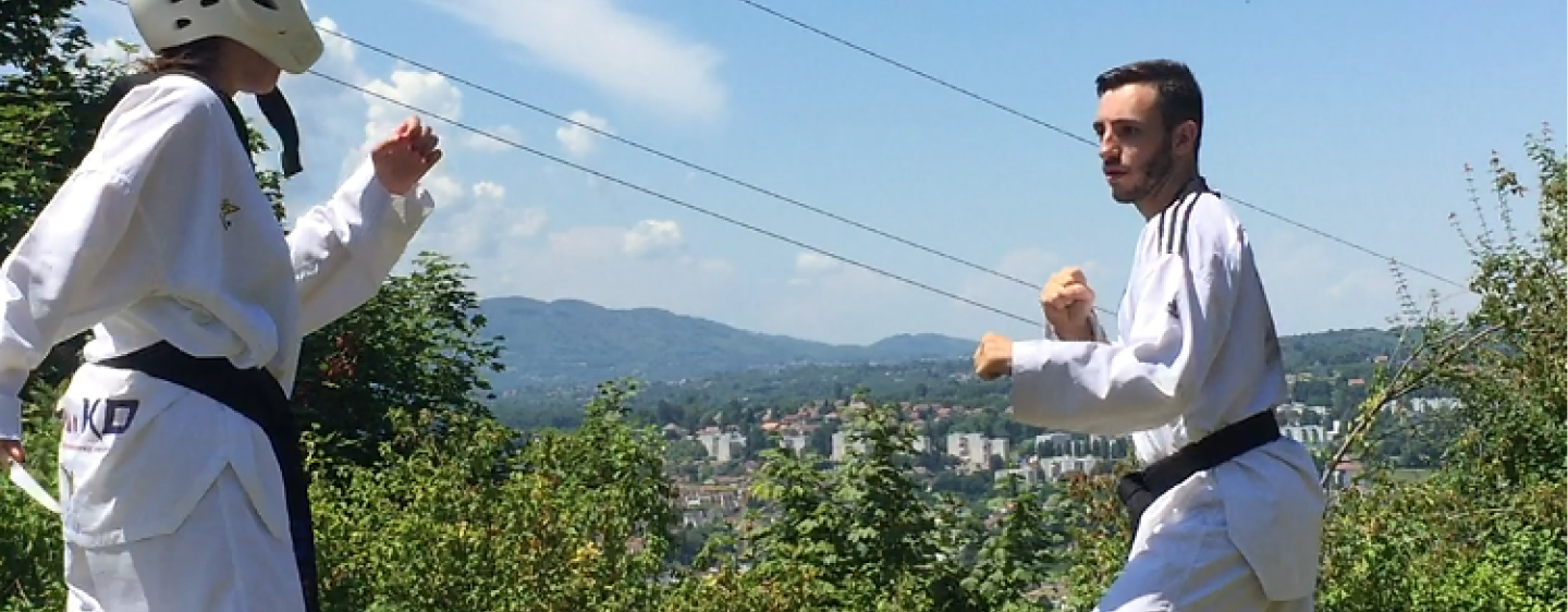 Deux personnes dont un homme de face font du taekwondo dans un parc